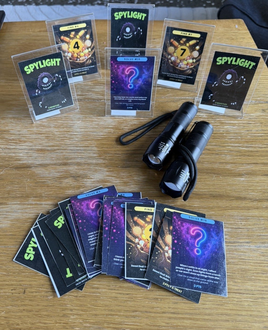 Spylight cards standing in clear holders on a table, with two torches beside them.